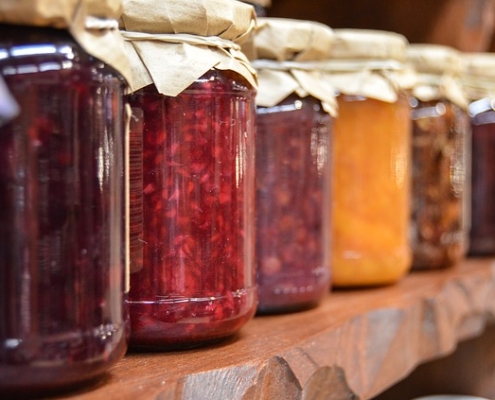 Photo of a line of different jams on a shelf.
